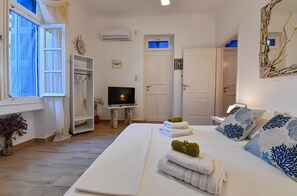 Hotellihuone, jossa on sänky, televisio, vaatekaappi, ovi ja ikkuna.