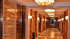 A luxurious hotel corridor with marble walls, ornate doors, and chandeliers. - Yangming Springs and Spa Resort (Ningbo)