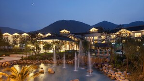 A hotel with multiple buildings, a fountain, and a mountain backdrop. - Yangming Springs and Spa Resort (Ningbo)