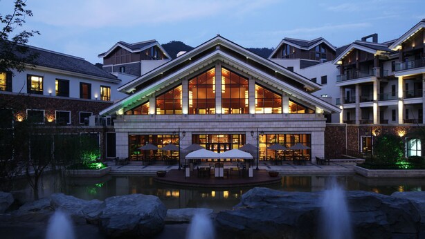 A hotel with a large central building, outdoor seating area, and a reflecting pool with rocks. - Yangming Springs and Spa Resort (Ningbo)