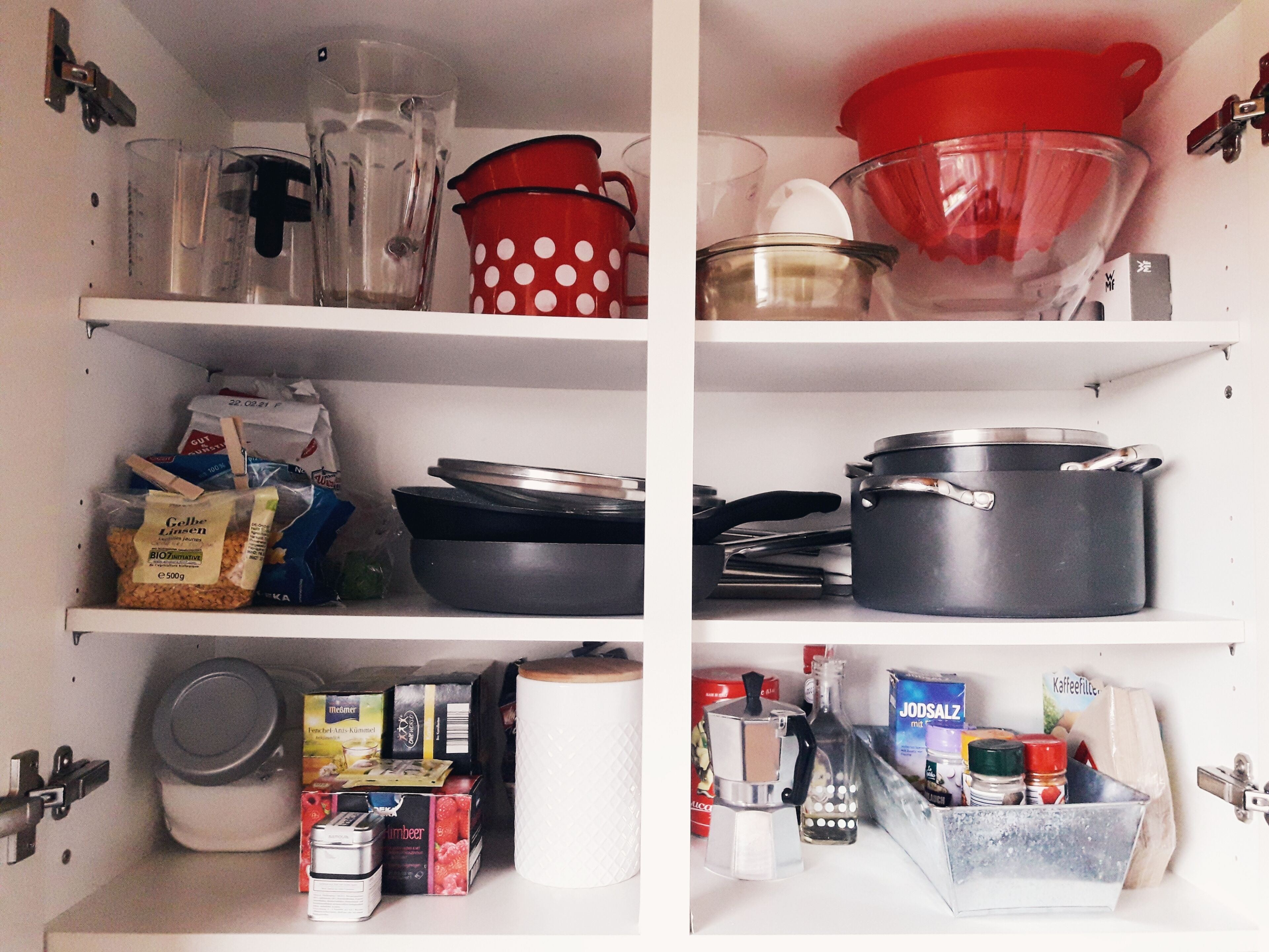 A kitchen with shelves containing various kitchenware, including pots, pans, and cooking utensils.