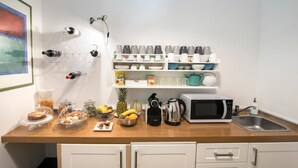 A kitchen with a wooden countertop, a microwave, a kettle, and various kitchen utensils. - The Andy House B&B (Naples)