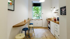 A compact kitchen with a wooden countertop, bar stools, a window with a view of greenery, and a hanging light fixture. - The Andy House B&B (Naples)