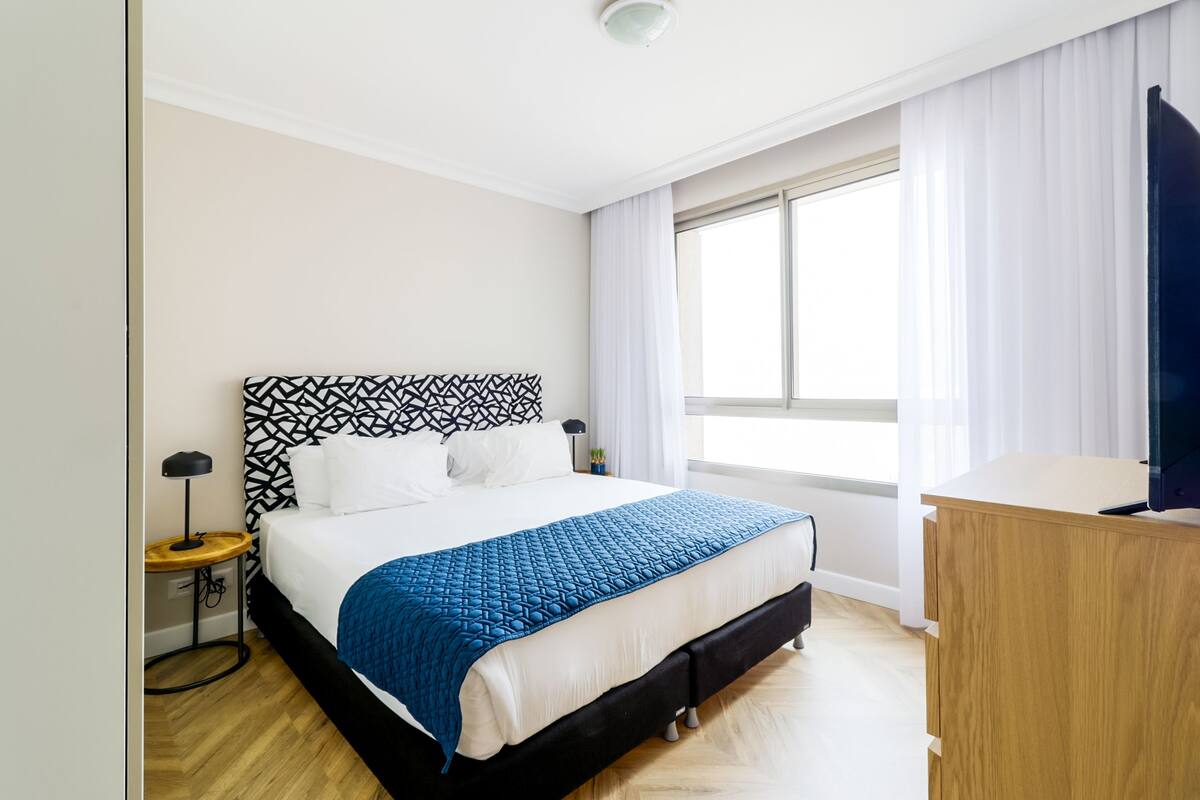 Une chambre à coucher avec un lit, une table de chevet, une lampe et un bureau en bois.