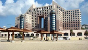 Un grand hôtel à plusieurs étages, doté d’un atrium central et d’un parking situé à l’avant.