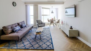 Un salon moderne comprenant un canapé, une table basse et un coin repas avec des chaises.