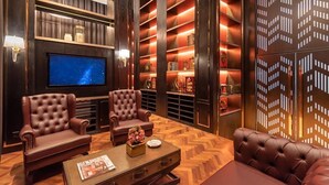 Una sala de estar lujosa con sofás de cuero, un televisor de pantalla plana y un piso de madera con patrón de espiga.