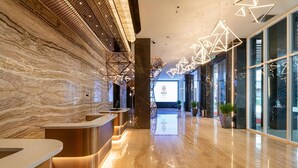Un moderno vestíbulo de hotel con paredes de mármol, un mostrador de recepción e iluminación geométrica.