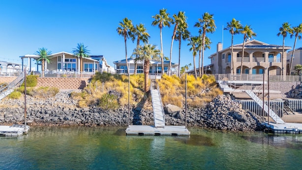 A waterfront property with a clear view of the water, a dock, and a building with a balcony overlooking the water.