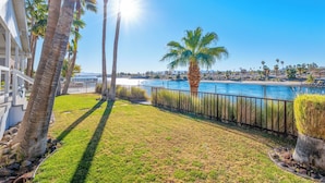 A coastal property with a grassy lawn, palm trees, and a view of the ocean.