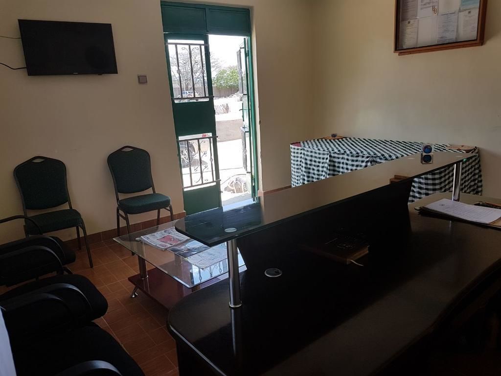 A reception area with a desk, chairs, a television, and a door leading outside.