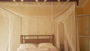 Ein Bett mit Baldachin, einem hölzernen Kopfteil und einer roten Bettdecke.