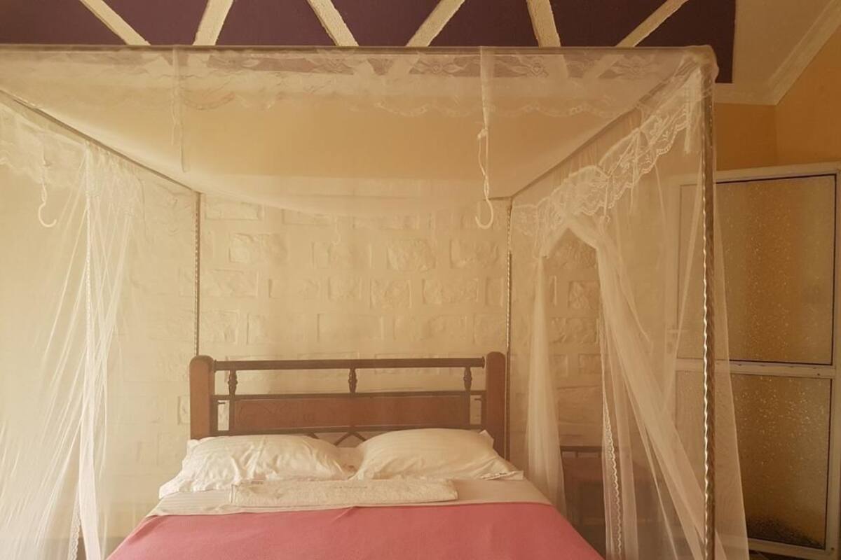 A bed with a canopy, a wooden headboard, and a red bedspread.