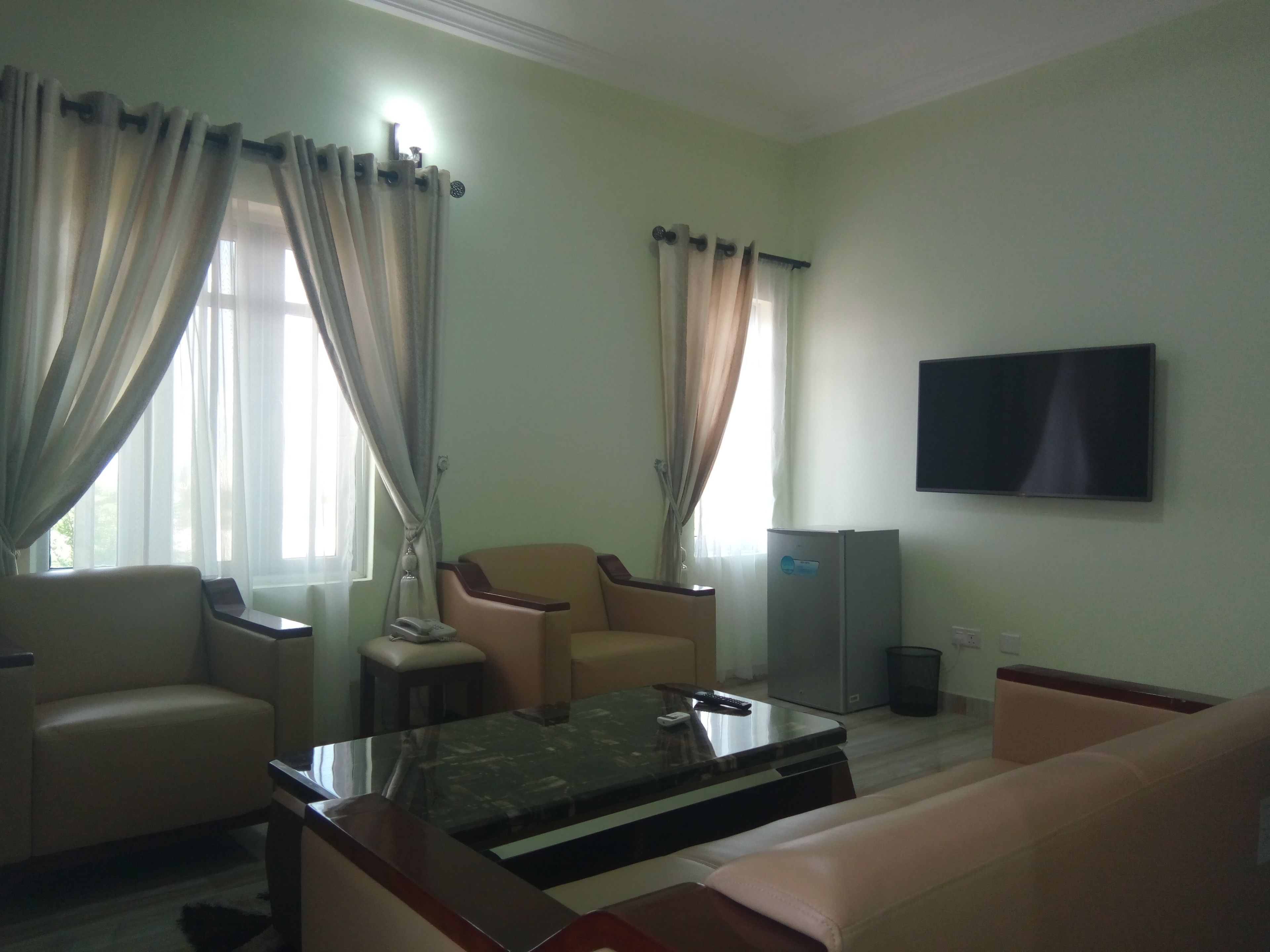 A living room with a sofa, armchair, coffee table, TV, and a small table with a lamp.
