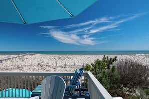 A beach view from a balcony with a blue umbrella, two Adirondack chairs, and a wooden deck. - PET Friendly 2BR OCEANFRONT Perfect for Small Family or Couple (Long Beach Township)