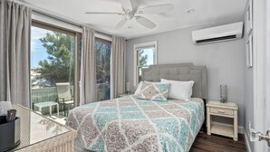 Une chambre à coucher comprenant un lit, une table de chevet, une chaise, une table et un ventilateur de plafond.