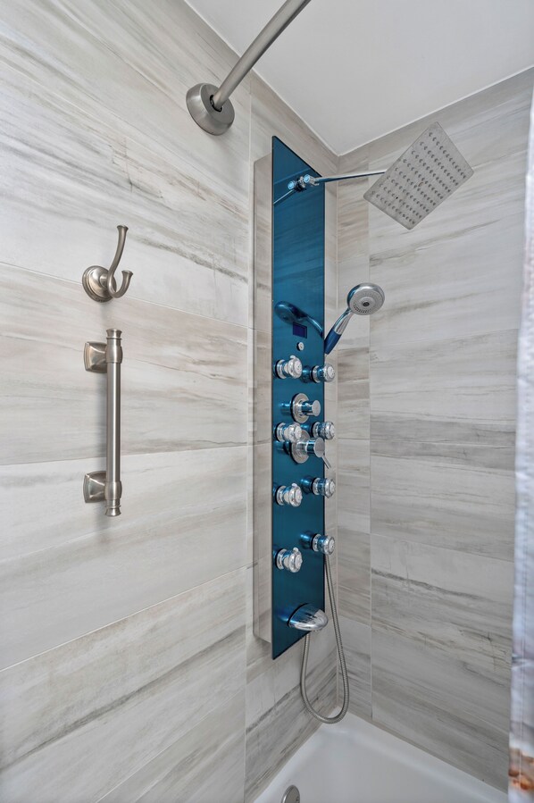 A modern shower with multiple heads, a handheld showerhead, and a rain shower head. - PET Friendly 2BR OCEANFRONT Perfect for Small Family or Couple (Long Beach Township)