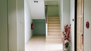 A hallway with a tiled floor, a staircase, and a door with a number plate. - Rawai Guesthouse (Chalong)