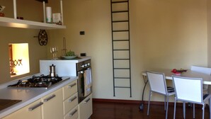Una cucina con mobili bianchi, un fornello e un'area pranzo con tavolo e sedie.