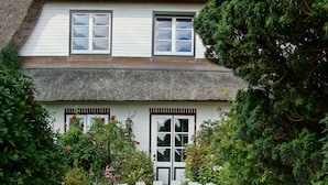 Ein Haus mit einem Strohdach und einem weißen Zaun.
