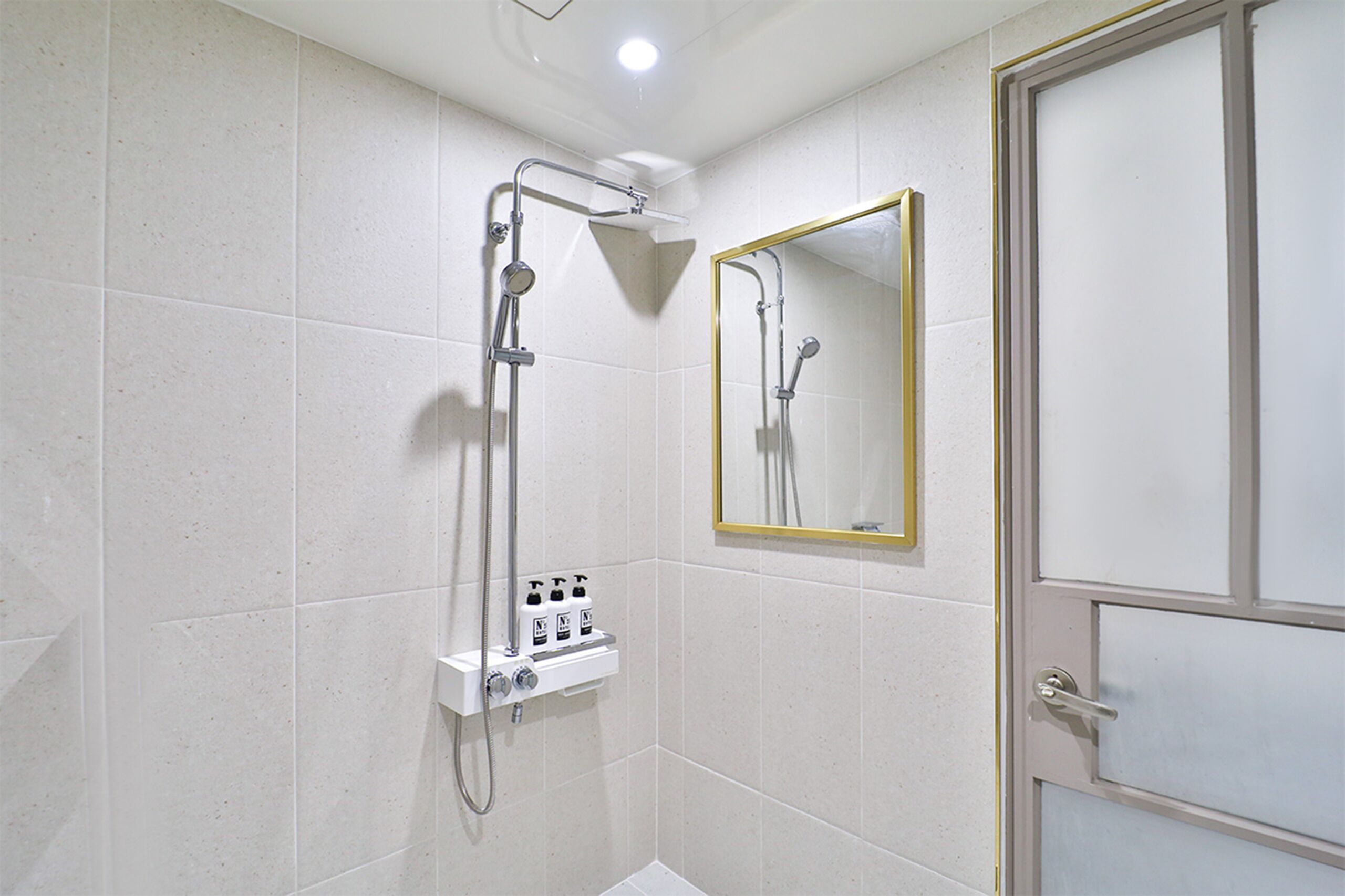 Un baño con ducha, espejo y puerta.