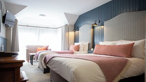 A hotel room with a large bed, a sofa, a TV, and a desk. - McGrorys (Culdaff)