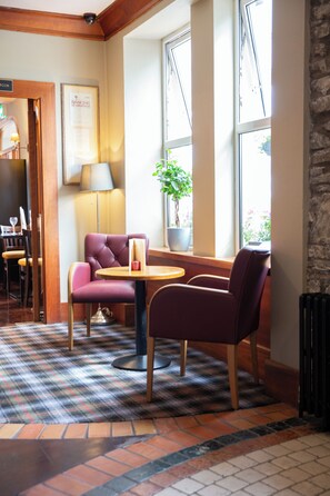 A cozy seating area with a plaid carpet, a table, and two chairs. - McGrorys (Culdaff)