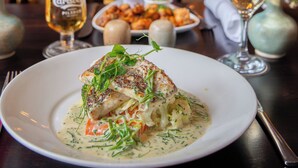 A dining table with a plate of food, a glass of beer, and a vase with flowers. - McGrorys (Culdaff)
