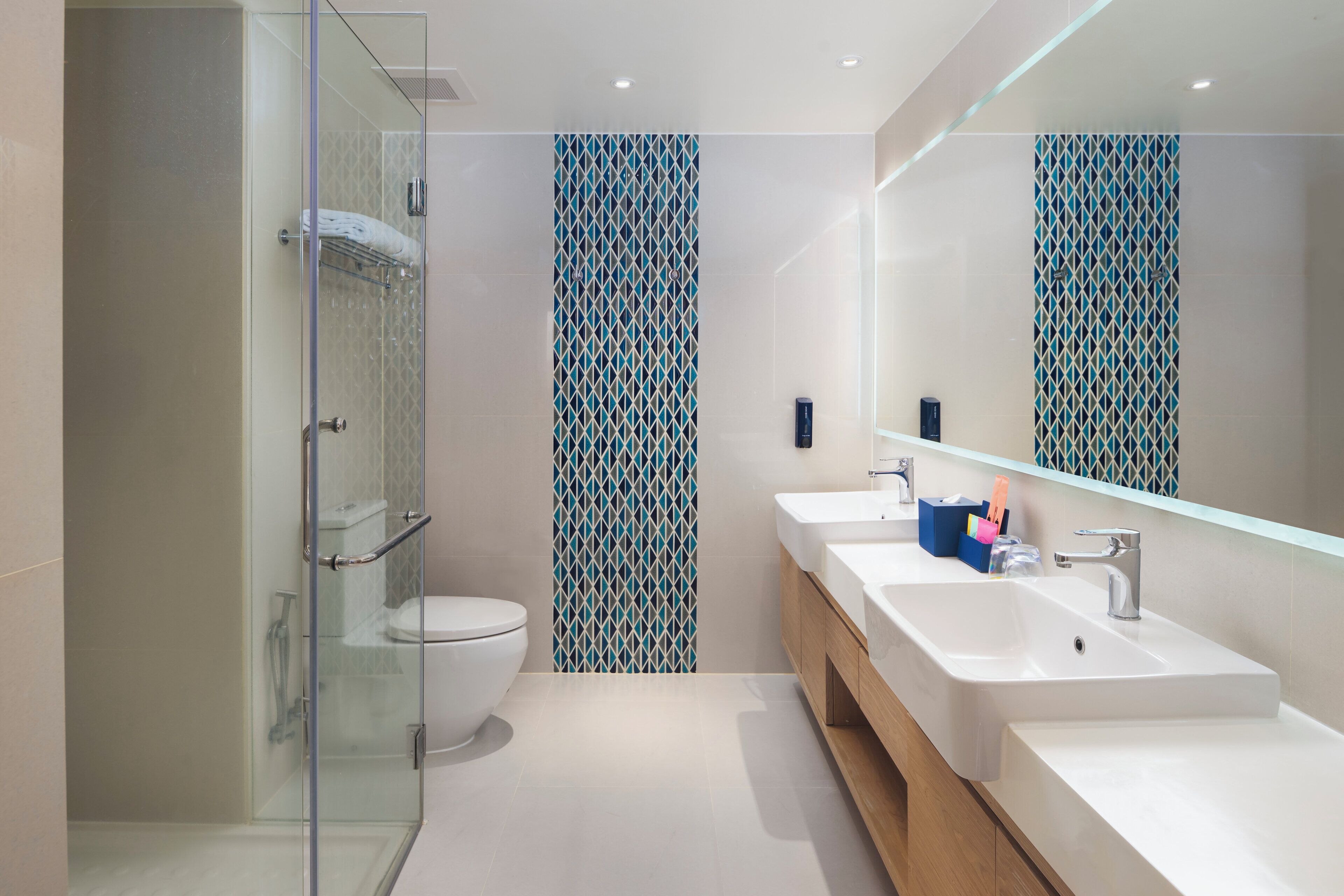 Un baño moderno con cabina de ducha de vidrio, inodoro blanco y tocador con espejo.