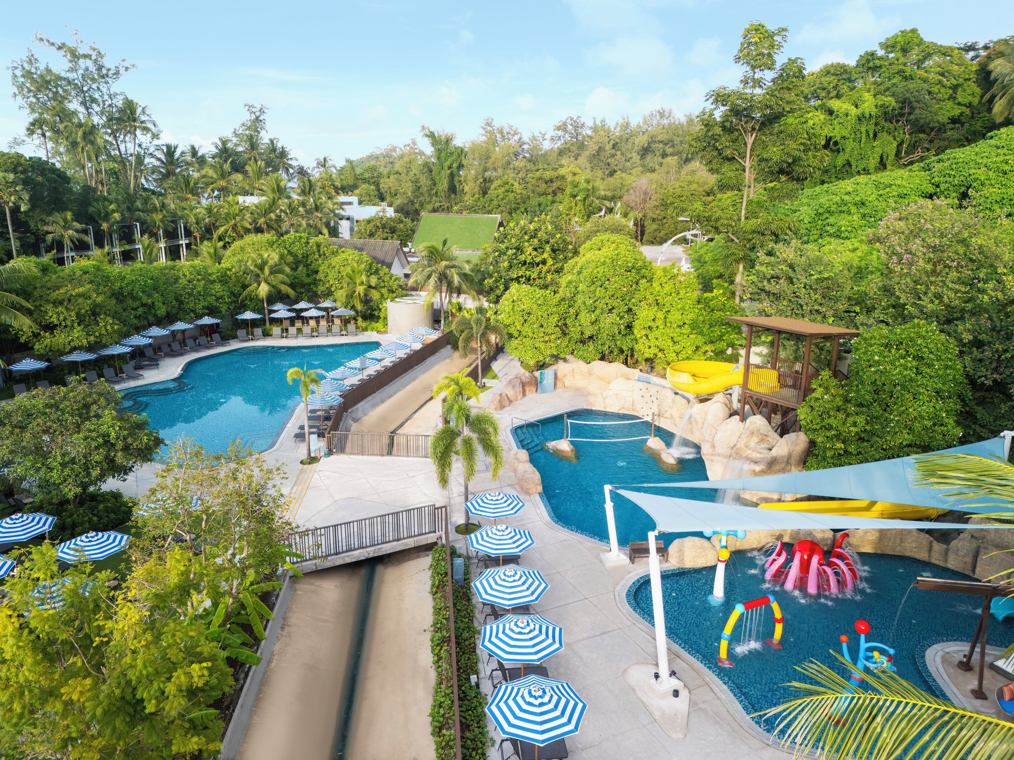 A resort with multiple swimming pools, lounge areas with umbrellas, and lush greenery.