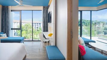 Habitación de hotel con un ventanal grande, cama, sofá, mesa de comedor y televisor.