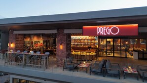 A restaurant with outdoor seating, a neon sign, and a brick facade. - OZO Phuket (Karon)