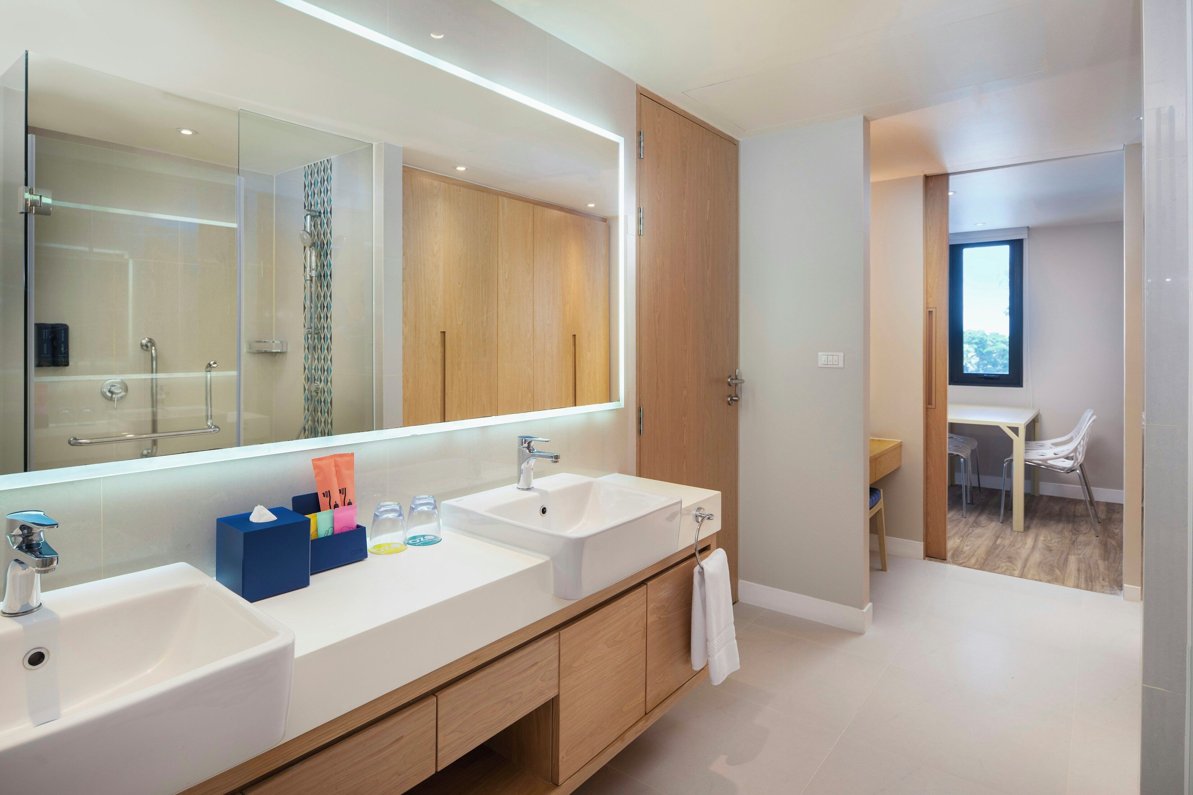 Un baño moderno con dos lavamanos, un espejo grande y armarios de madera.