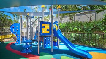 A playground with a blue slide, climbing structures, and a covered play area.