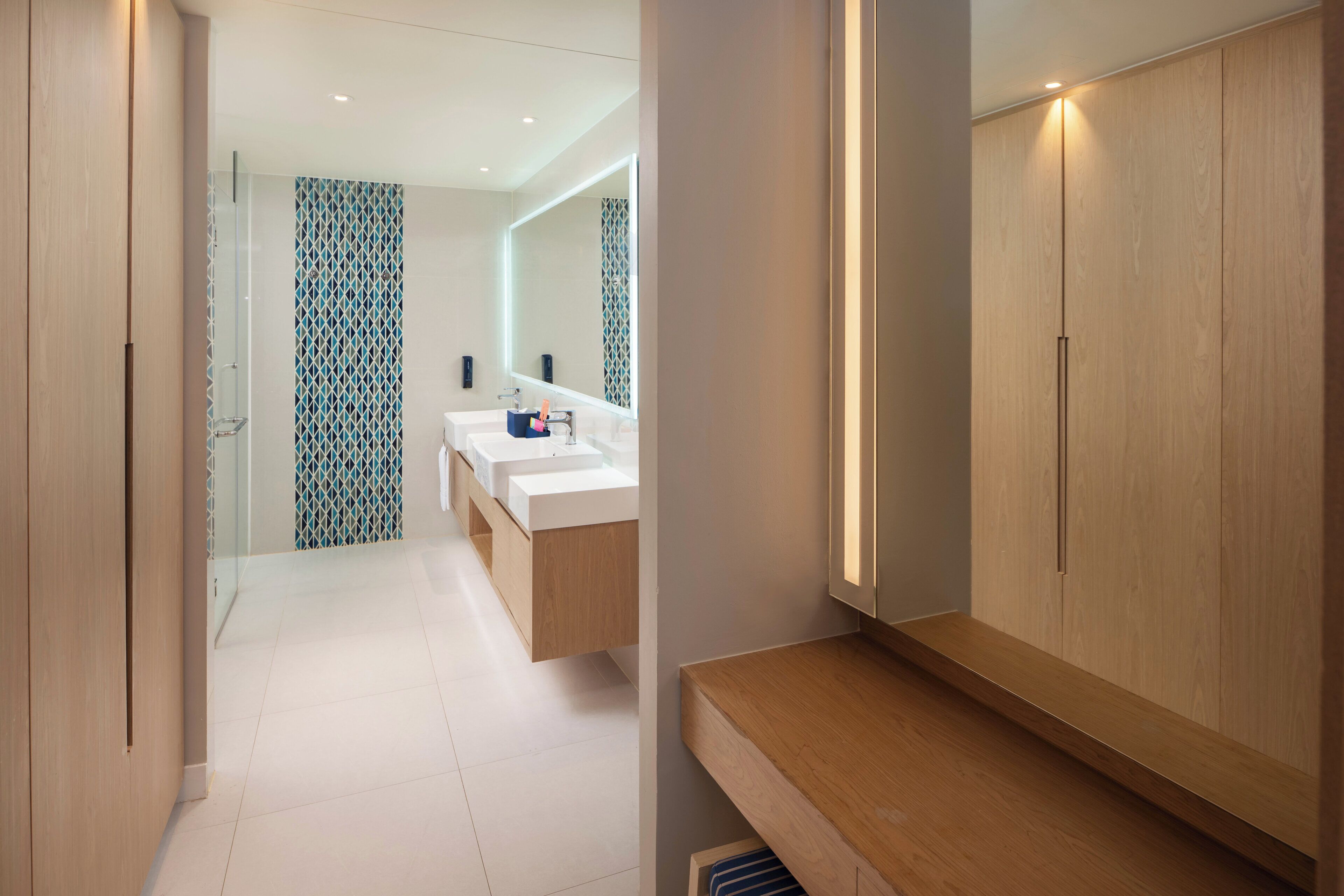 Un baño moderno con tocador, dos lavamanos y espejo.