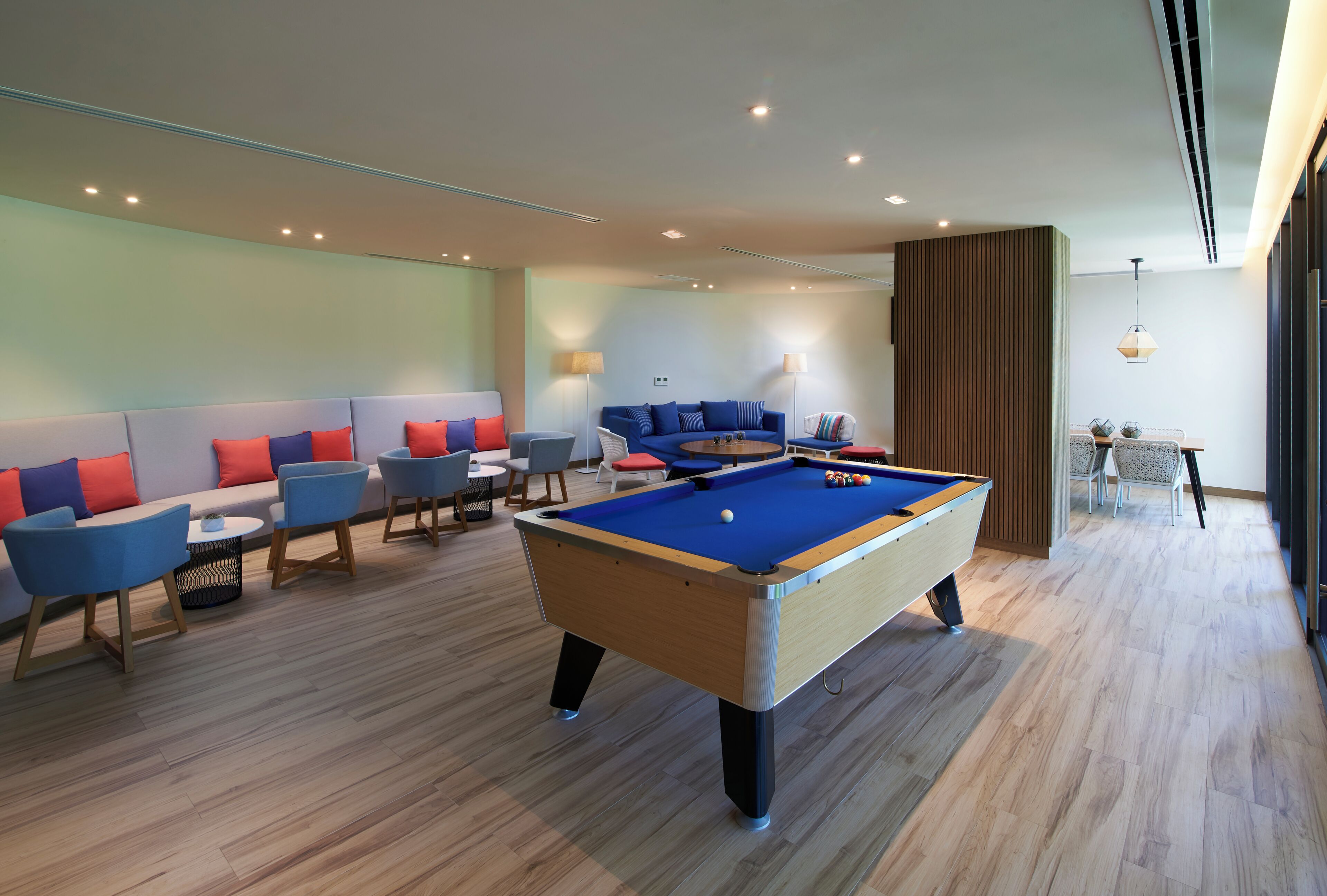 A pool table in a modern lounge area with seating and ambient lighting.