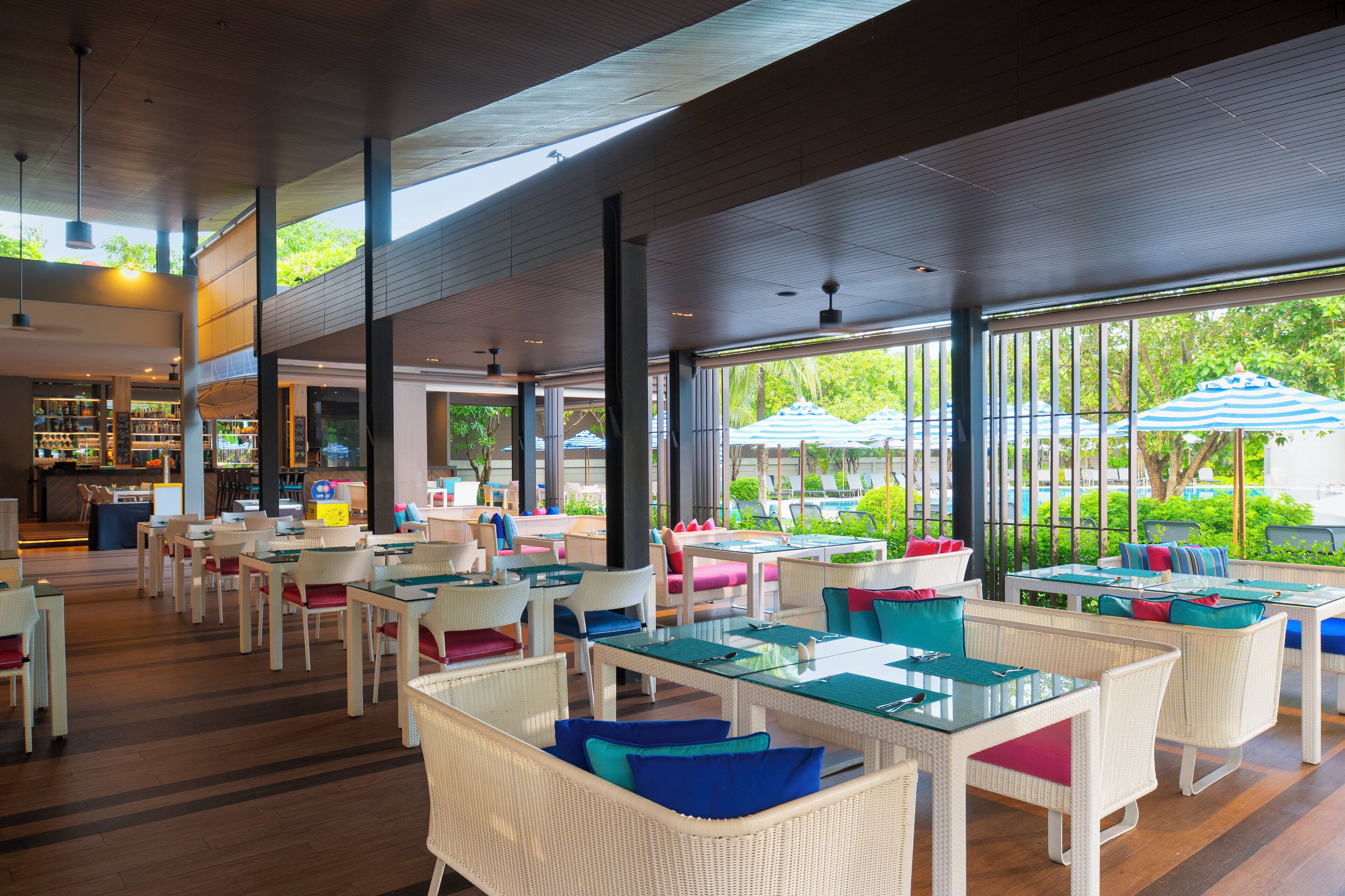 A spacious indoor dining area with wicker furniture and large windows offering views of the outdoors.