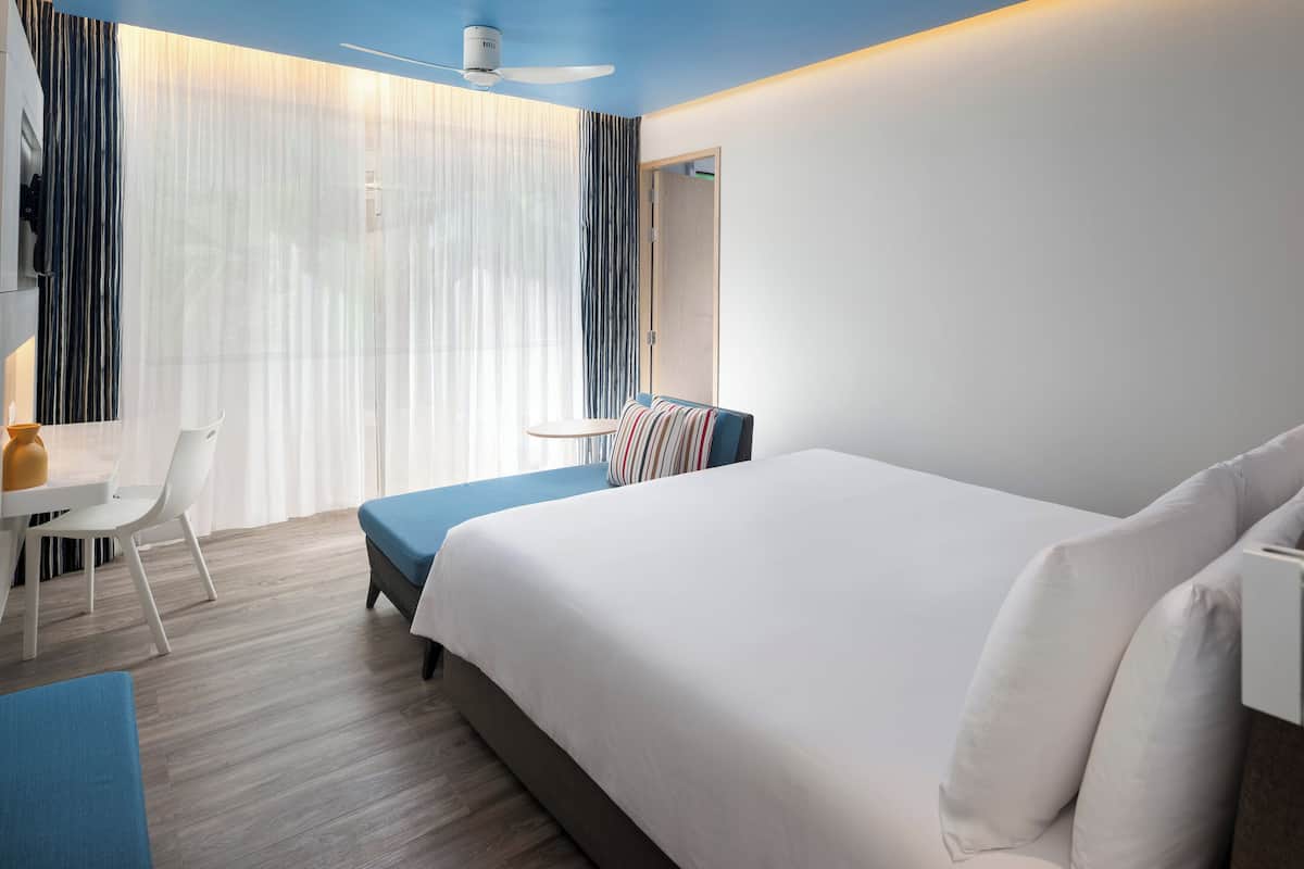 A modern hotel room with a large bed, a desk, and a chair.