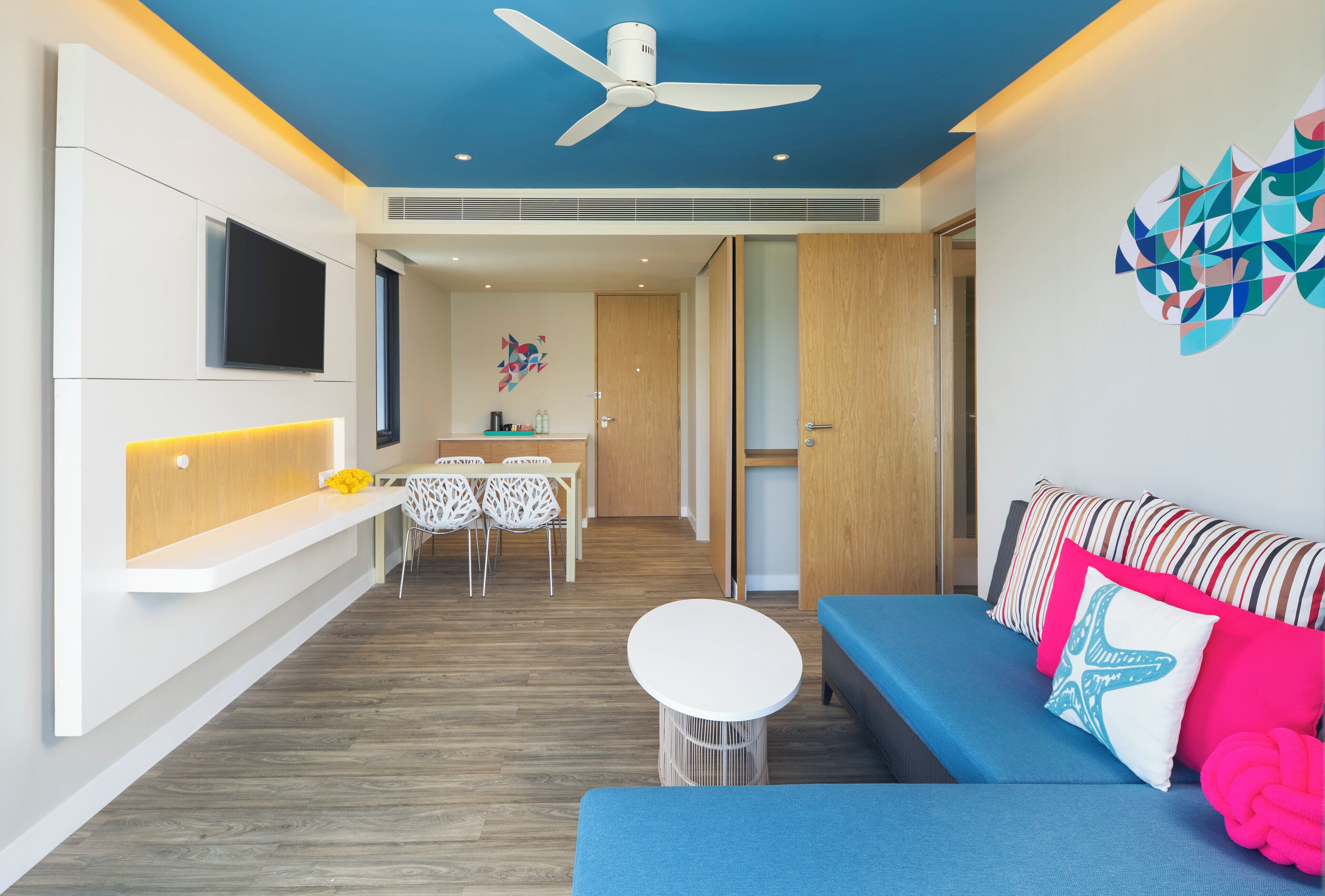 Una sala de estar moderna con un sofá azul, una mesa redonda blanca y un ventilador de techo.