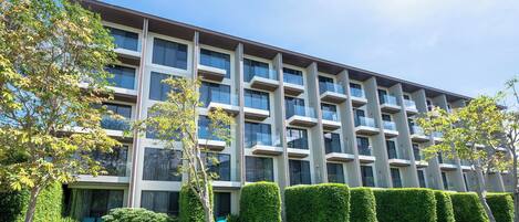 A multi-story building with a modern architectural design, featuring balconies and large windows.