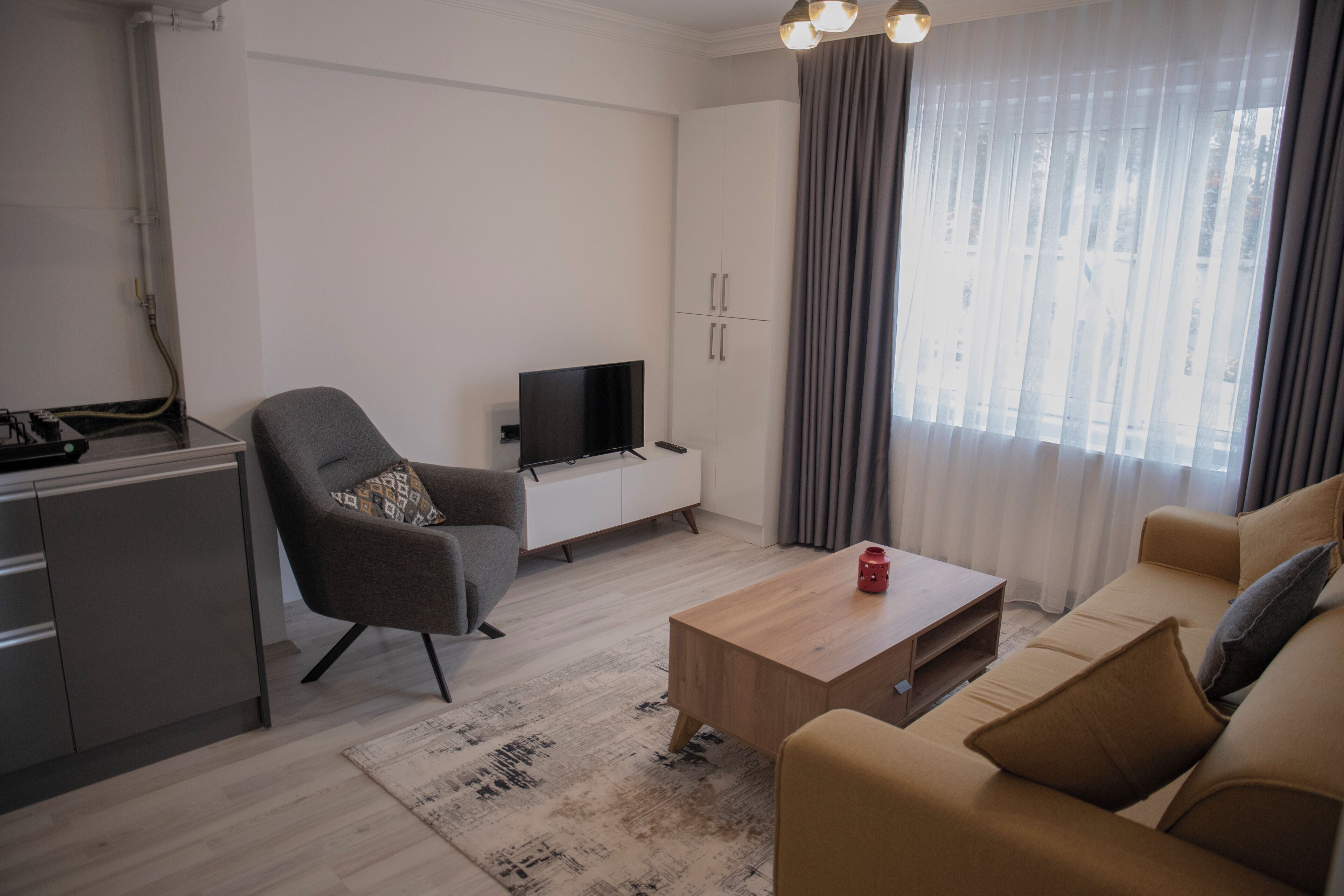 Un salon moderne comprenant un canapé, un fauteuil, une table basse, un téléviseur et un meuble.