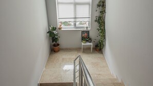 Eine Treppe mit Handlauf, ein Fenster mit Pflanzen und ein kleiner Tisch mit einer Pflanze.