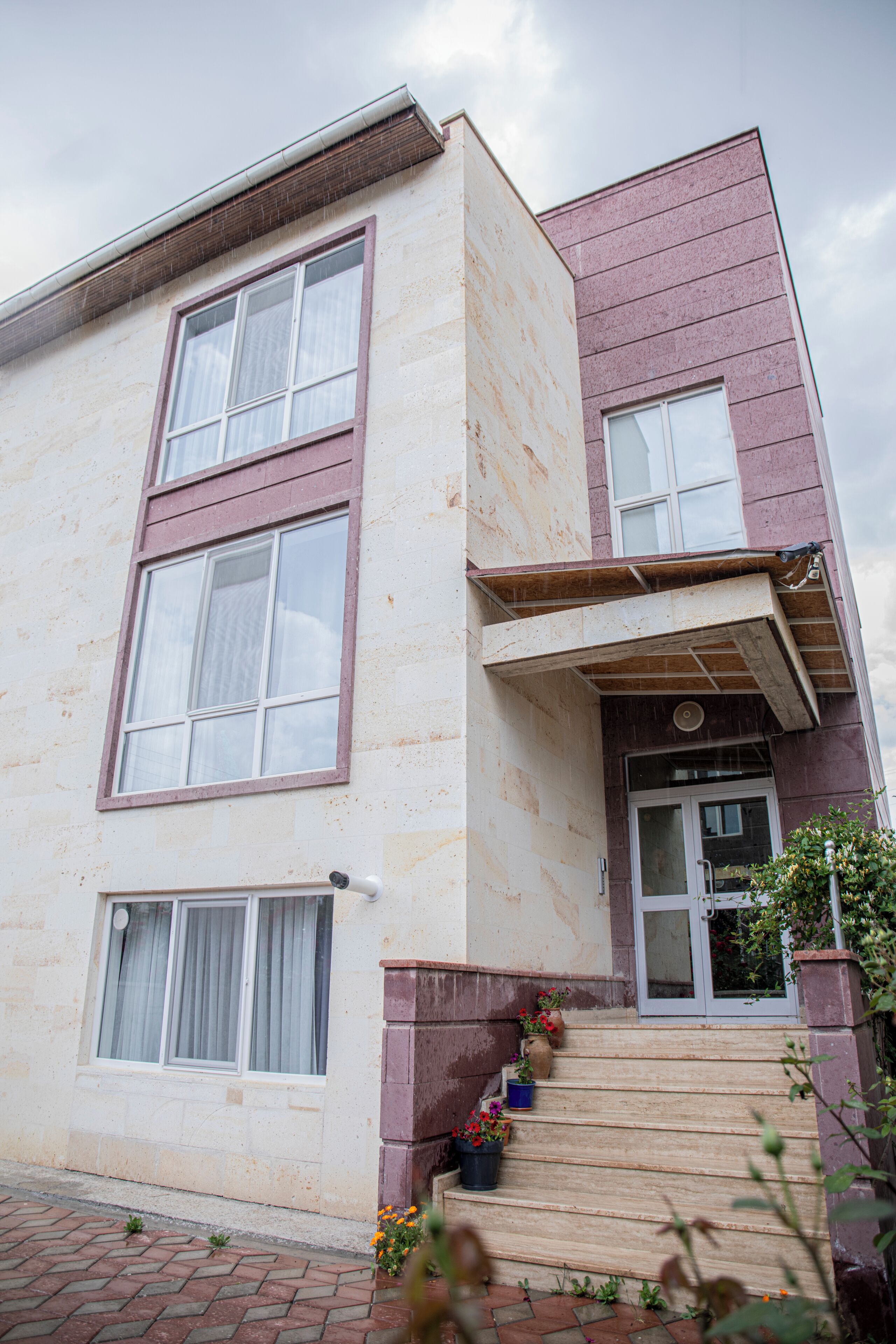 A two-story building with a flat roof, large windows, and a small porch area.