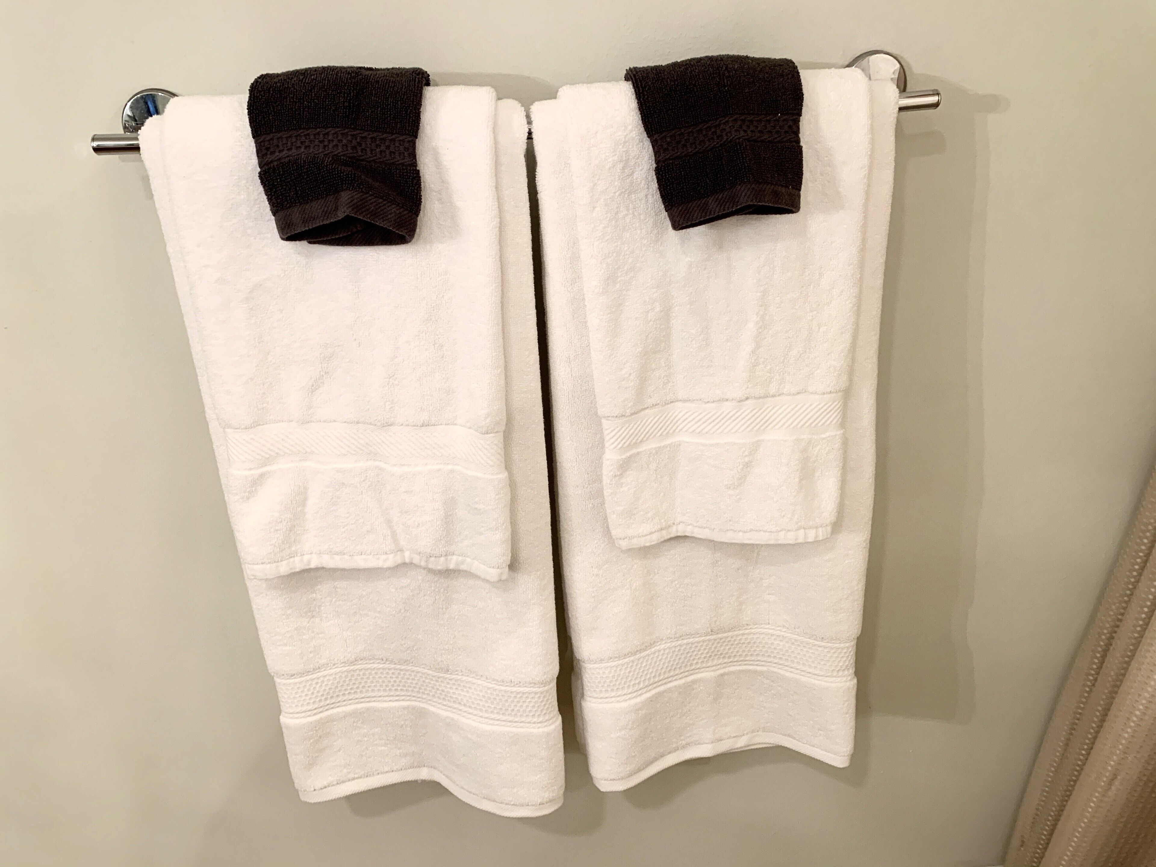 Two white towels hanging on a metal towel rack.