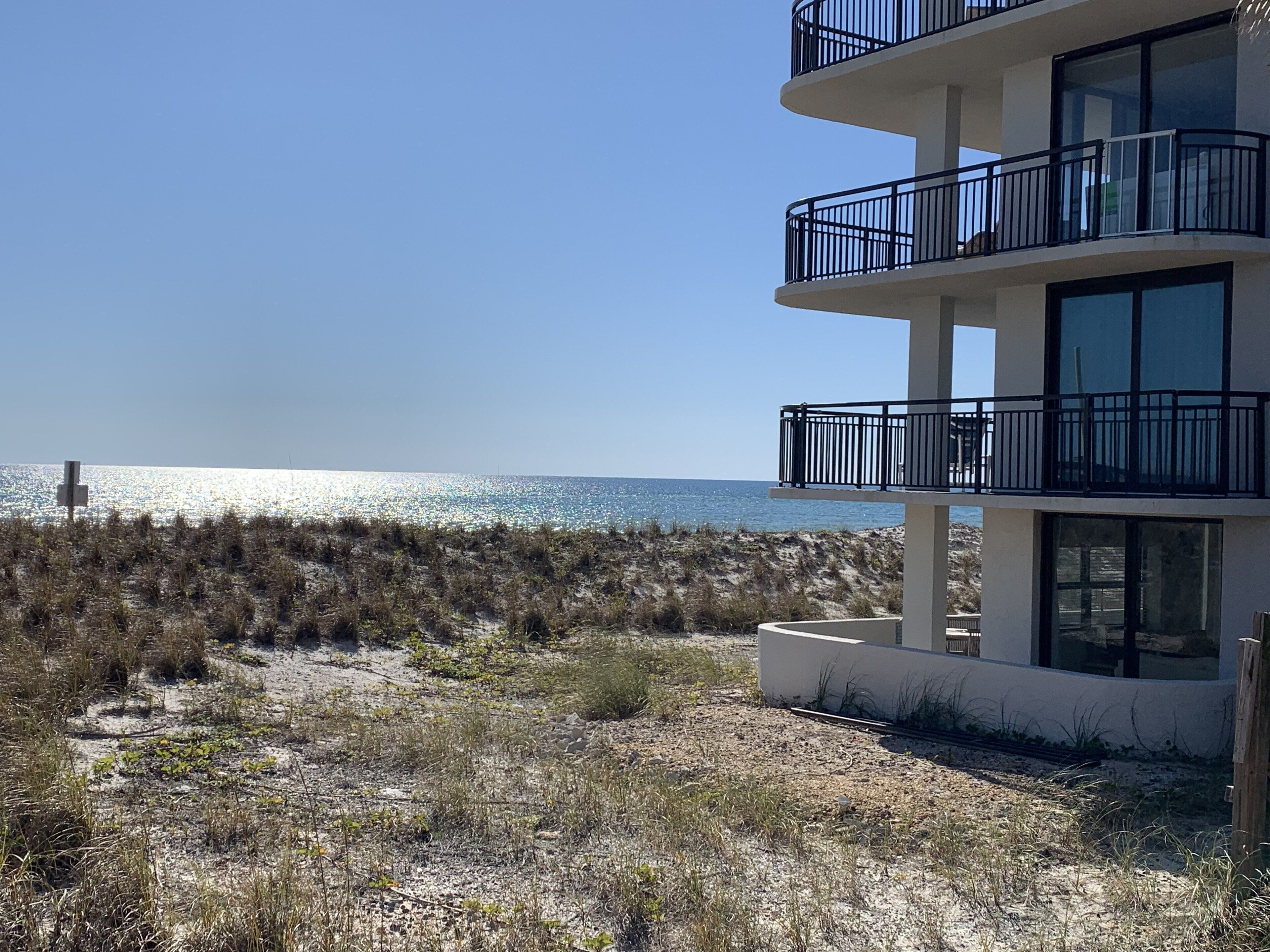 Ein Gebäude direkt am Strand mit mehreren Balkonen mit Blick aufs Meer.
