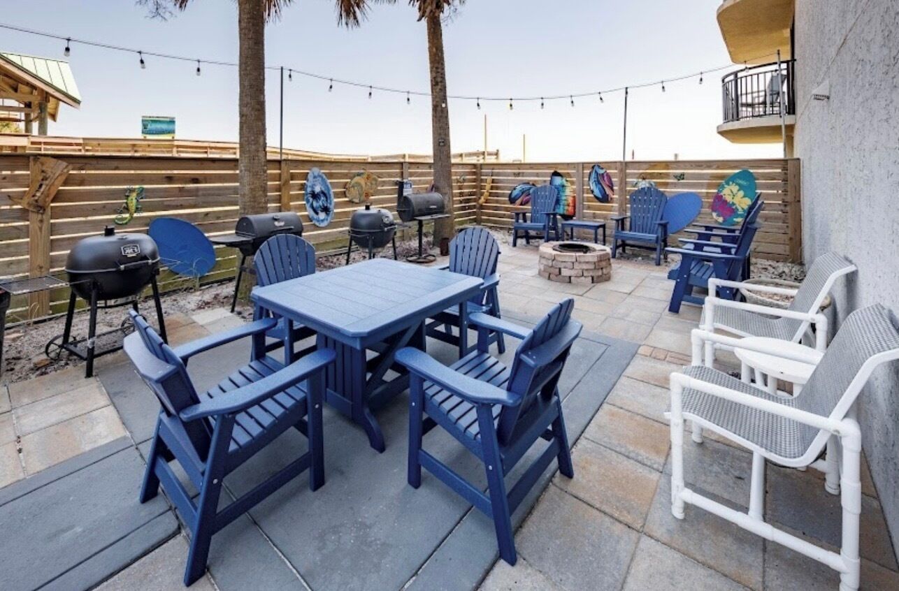 An outdoor patio with a table and chairs, a grill, and a fire pit.