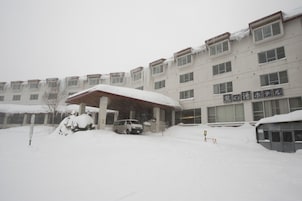 A multi-story building with a covered entrance and a sign in Japanese.