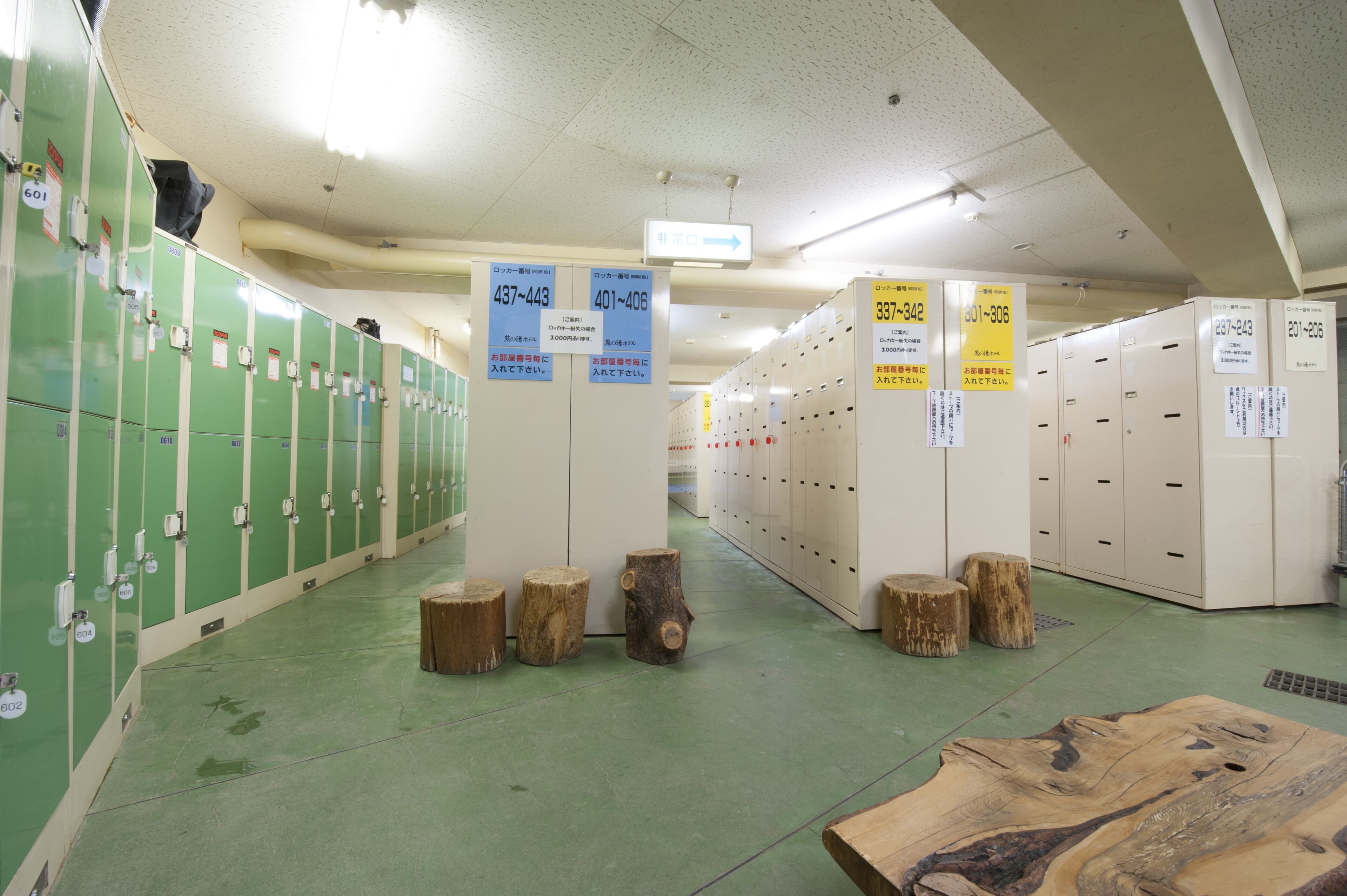 A locker room with green lockers on the left and white lockers on the right, each with numbered signs.