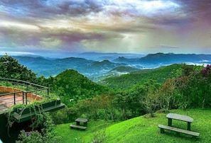 A lush green landscape with a bench and a small platform overlooking a valley. - Haze and Kites Resort Munnar (Devikolam)