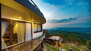 A modern hotel with a curved balcony overlooking a lush landscape. - Haze and Kites Resort Munnar (Devikolam)